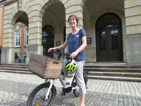 Klimaschutzmanagerin Leslie Matthiesen auf einem der elektrischen Diensträder vor dem Kreishaus
